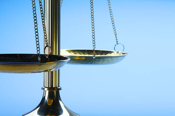 A brass justice scale in front of a blue background.