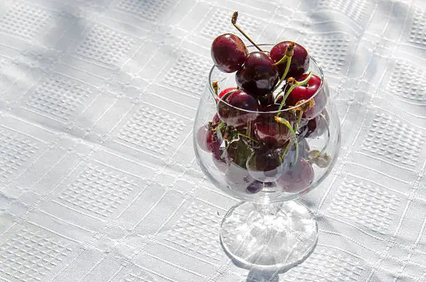 Sweet cherry in a crystal glass on white tablecloth
