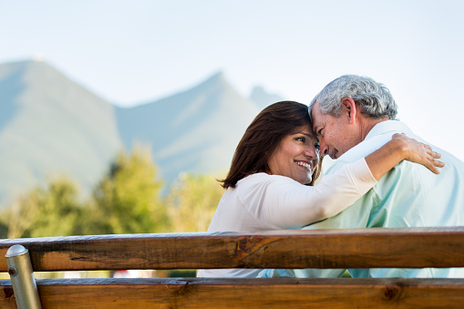 Loving happy mature couple sitting on bench in a park