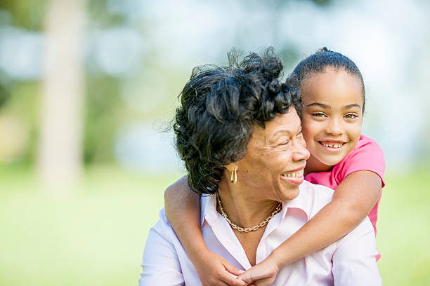 Loving cute granddaughter hugging her grandmother. Happy family.  Having good times with grandparent outdoors. Love, connection, bonding  concept. Soft light toned