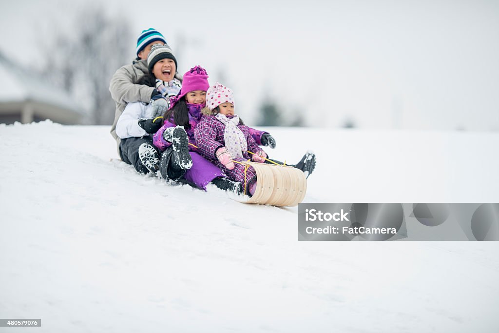 Family Tobogganing A family (father, mother, and daughters) enjoying winter by riding a toboggan sled/tube down a snowy hill in winter. Sledding Stock Photo Family Tobogganing A family (father, mother, and daughters) enjoying winter by riding a toboggan sled/tube down a snowy hill in winter. Sledding Stock Photo