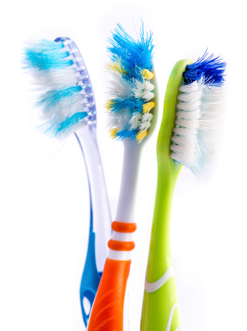 Old used colorful toothbrushes isolated on white background