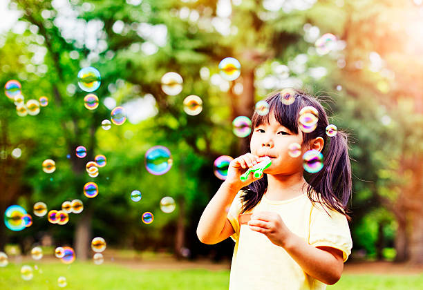 istock Little girl blowing soap bubbles 480585466