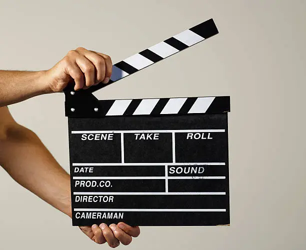 Man holding film slate on white background.