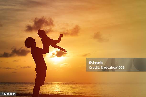 Father And Little Daughter Silhouettes At Sunset Stock Photo - Download Image Now - 2015, Adult, Baby - Human Age