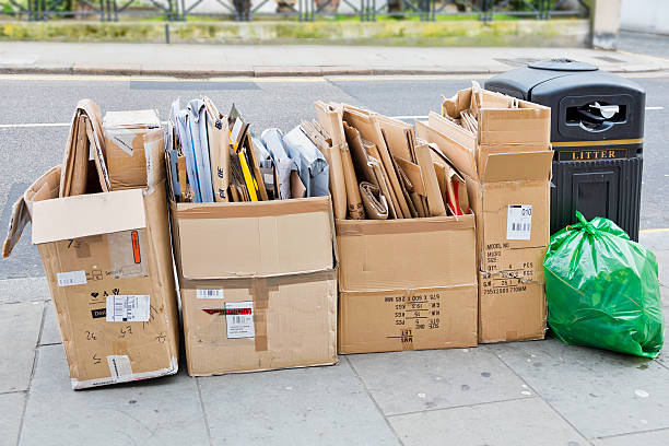 Discarded Cardboard Boxes A neatly arranged stack of discarded cardboard boxes awaiting collection by refuse disposal crew on a street pavement in London. curb photos stock pictures, royalty-free photos & images