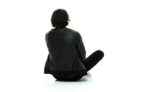 Rear view of man sitting on floor and looking away