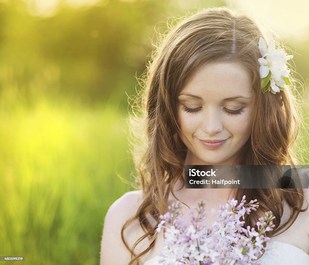 Beautiful spring girl with flowers on the meadow Beautiful woman with flowers in spring sunshine. Girl is holding a lillac on the green meadow. Formal Garden Stock Photo