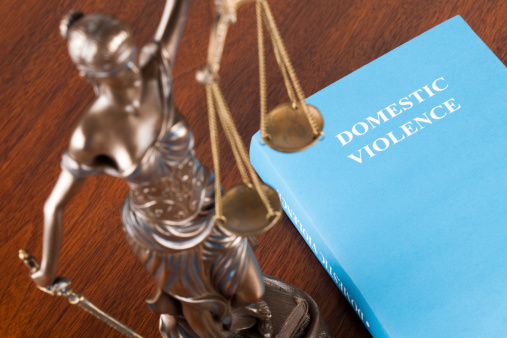 A mock law book on domestic violence next to Lady Justice. Selective focus.