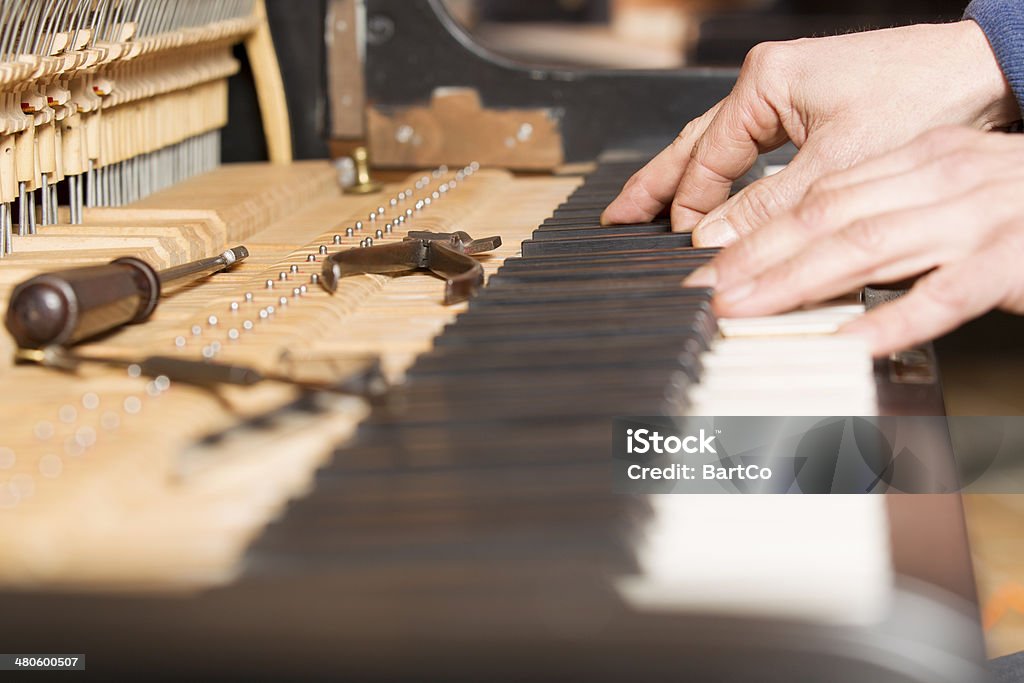 Piano tuning tool Piano technician at work checking key, focus on hand Piano Tuner Stock Photo