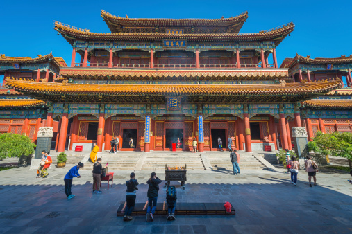 Beijing, China - 25th September 2013: People praying with incense sticks in a quiet courtyard at the Lama, or Yonghe, Temple, the iconic Buddhist monastery in the heart of downtown Beijing, China's vibrant capital city.