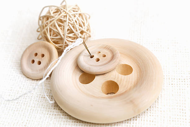 istock Wood buttons with needle and thread on linen fabric 480604733
