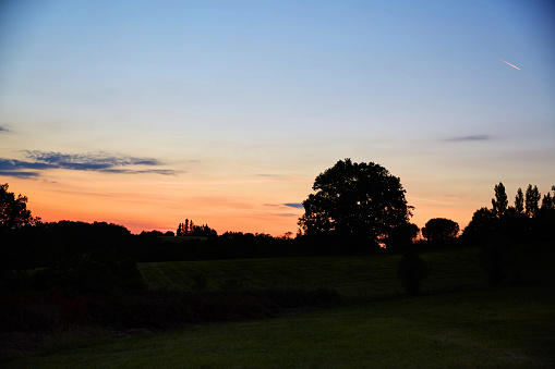 Setting sun behind hillside tree line