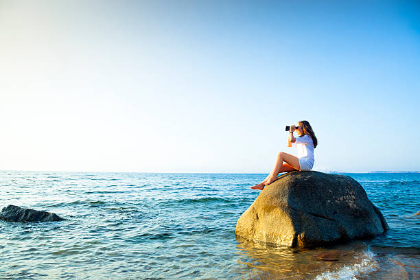 adolescent avec jumelles assis sur un rocher dans la mer. - only teenage girls teenager adolescence sea photos et images de collection