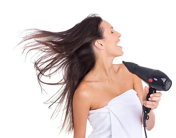 An attractive woman expressing enjoyment while drying her hair