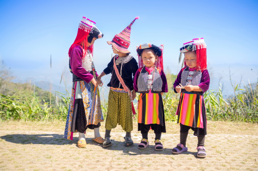 Chiang Mai, Thailand - January 25, 2014: Group of Lisu hill tribe children posing for Tourists in Chiang Mai. They wear their traditional clothing from gaily-coloured cloth stitched into outfits trimmed with row upon row of vari-coloured strips of cloth. There are approximately 21000 Lisus living in Thailands northern provinces of Chaing Mai, Mae Hong Son and Chiang Rai. The Lisu people are a Tibeto-Burman ethnic group who inhabit the mountainous regions of Burma (Myanmar), Southwest China, Thailand, and the Indian state of Arunachal Pradesh.
