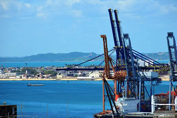 Salvador da Bahia, Bahia, Brazil: the port - container ship and gantry cranes - lower town, known as Bairro Comércio for its business district character - Cidade Baixa was largely built over a land fill - Baia de Todos os Santos and Cantagalo beach in the Background - photo by M.Torres