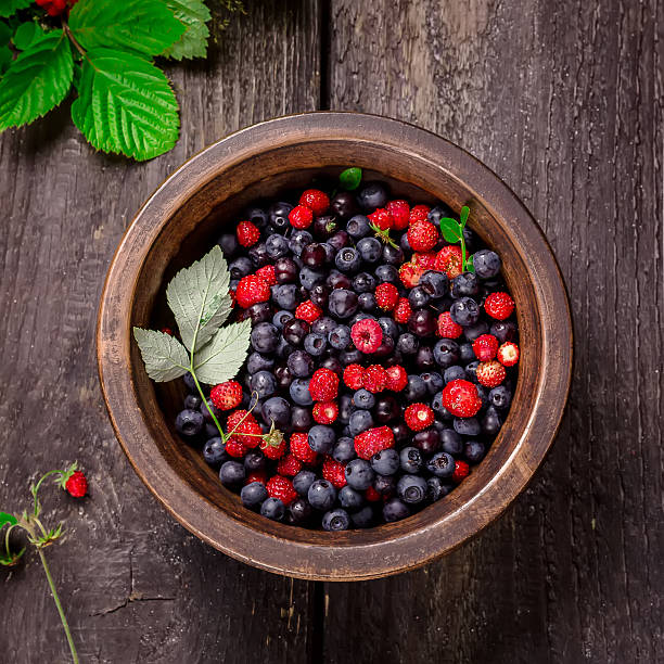 istock Bowl with wild berries on dark wooden background. 480614308