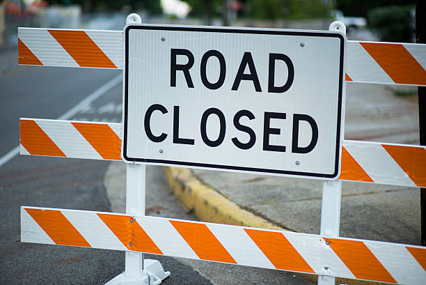 Close up of a Road Closed Sign during Road Construction this picture is a Close up of a Road Closed Sign during Road Construction. the sign is a warning for driver that the road ahead is closed due to road construction. the picture is of a road and sidewalk that are closed. the picture was taken during the day. and the lighting is natural sunlight.  road closed sign horizontal road nobody stock pictures, royalty-free photos & images