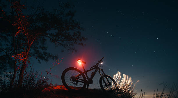 silhouette de vélo de montagne avec des lampes d'ambiance - phare arrière de véhicule photos et images de collection