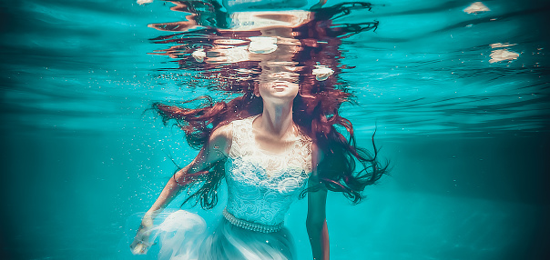 Young woman diving underwater, she's wearing red bikini and mask and diving flipper