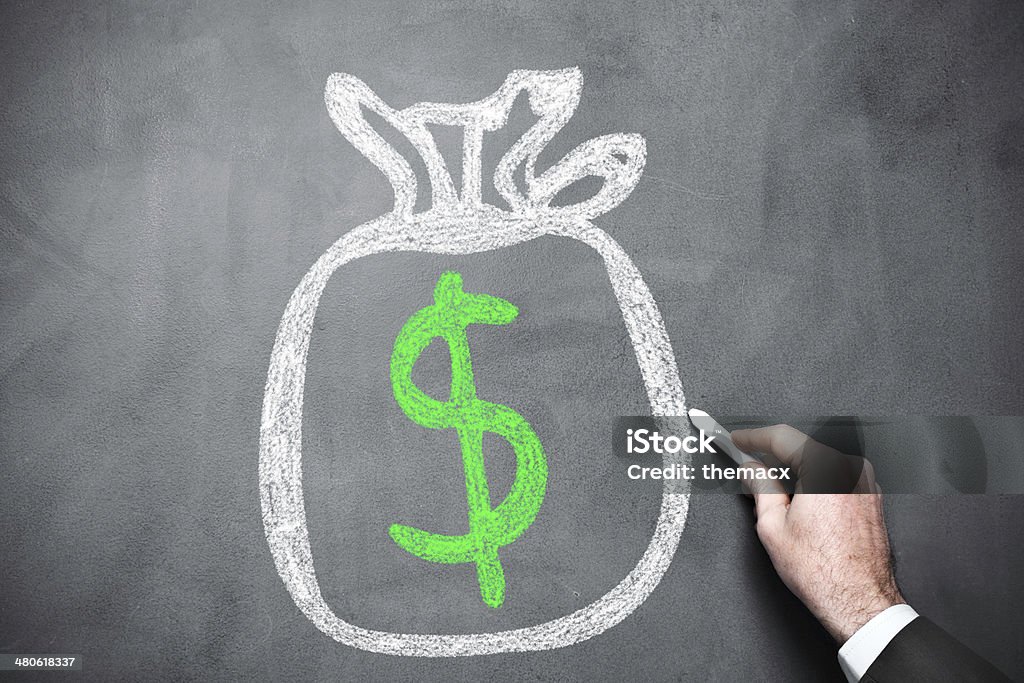 Moneybag on chalkboard Businessman drawing moneybag with dollar sign on blackboard. Abundance Stock Photo