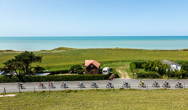 The Peloton - Tour de France 2015 Sainte Marguerite sur Mer, France - 09 July 2015: The peloton riding in line near the beach in Normandy during the stage 6 of Le Tour de France 2015 on 09 July 2015. cycling vest photos stock pictures, royalty-free photos & images