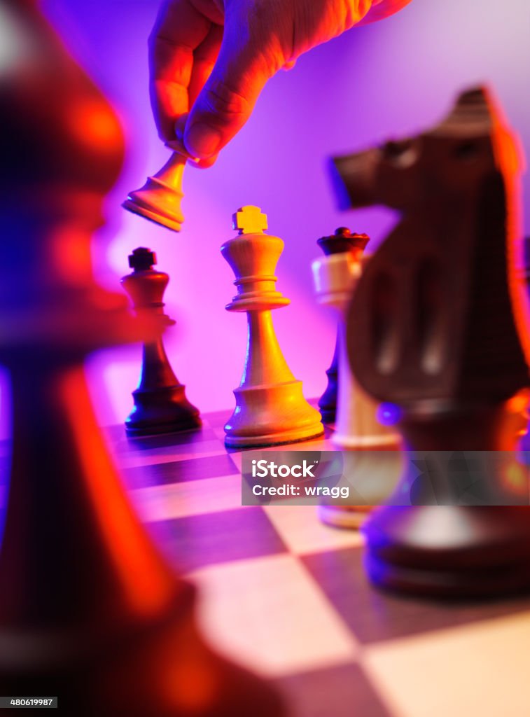 Pawn Taking the King Chess Piece in a Board Game Pawn taking the king chess piece on a chess board with coloured lighting. Bishop - Chess Piece Stock Photo