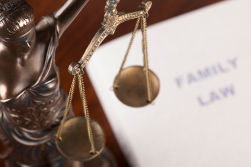 Family law handbook(mock book cover) next to Lady of Justice statuette. High angle studio shot.