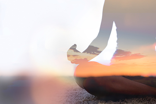 Mindful, calm and relaxed woman meditating outdoors at the beach sitting in the lotus position. Closeup of a Fit and zen female doing yoga during sunrise outside at the sea or ocean shore