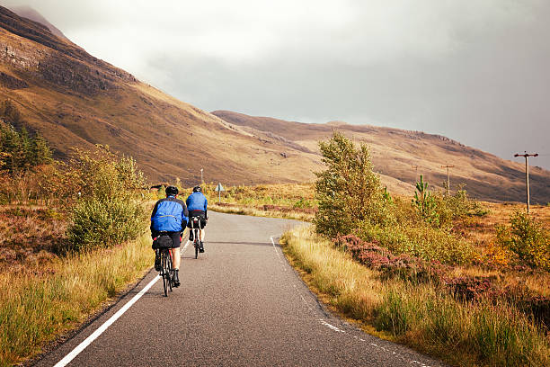 Ardelve, UK - September 24, 2011: Two cyclists ride their bikes on a small back road through Scotland's Wester Ross.