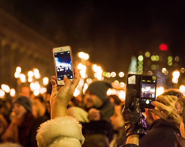 Taking photos of a celebration with smartphones Edinburgh, UK - December 30, 2014: People using smartphones to photograph participants in the annual torchlight procession in Edinburgh's city centre, part of the Hogmanay celebrations. hogmanay photos stock pictures, royalty-free photos & images