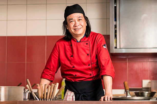 Asian man in yellow shirt with a gesture or expression of surprise when there is cookie in his mouth