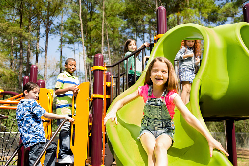 happy child having fun on slide at outdoor water park. summer vacation