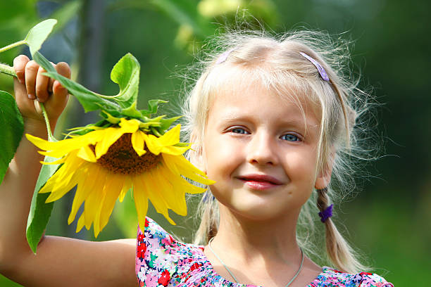 Child playing in sunflower field on sunny summer day. little girl plays with sunflowers.
