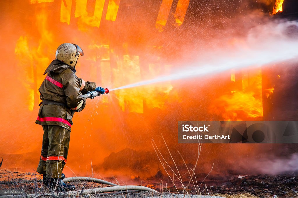Fireman extinguishes a fire Fireman extinguishes a fire in an old wooden house Fire - Natural Phenomenon Stock Photo