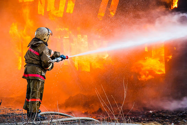 Fireman extinguishes a fire Fireman extinguishes a fire in an old wooden house extinguishing photos stock pictures, royalty-free photos & images