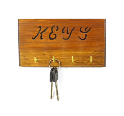 A wood key rack holding a single set of truck keys on a white background.