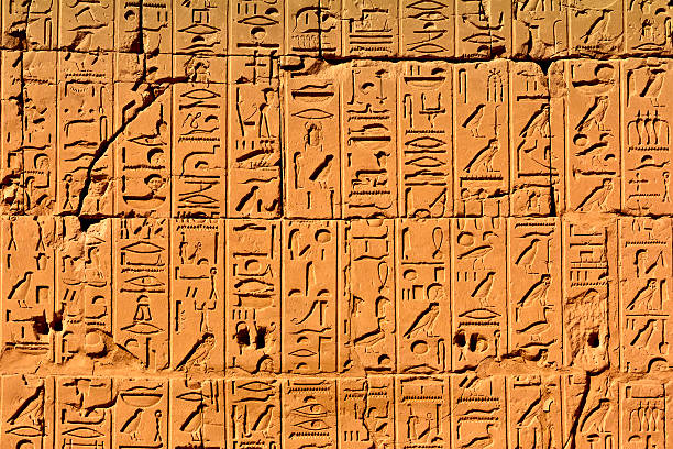 Ancient Egyptian writings, hieroglyphs and signs on a stone slab close-up. Historical Egyptian symbols, figures and symbols as text on the wall.