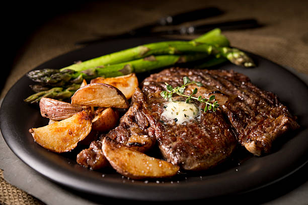 Grilled ribeye steak with steak fries and asparagus.  Very shallow DOF.