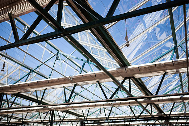 A stock photo of a glass greenhouse ceiling with partions and sprinkler system.