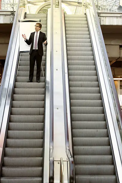 Man standing on an escalator with a flipchart, ready for his business presentation