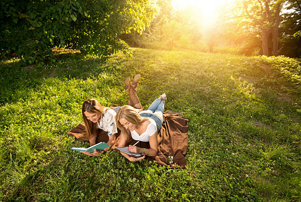istock Two female college students lying at the park and studying. 480644188