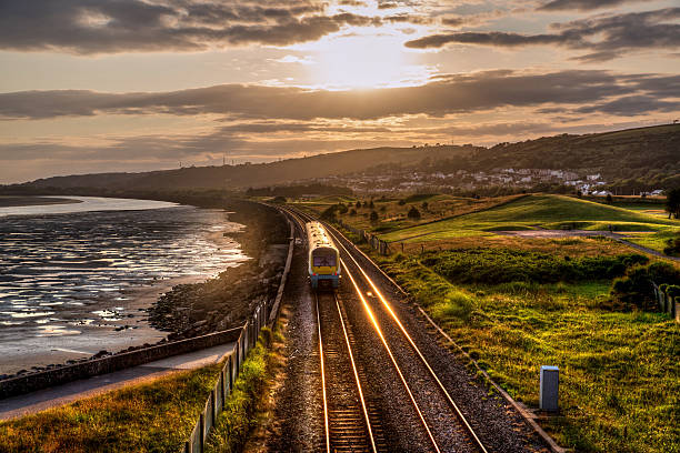 Train travelling past sea wall at sunset