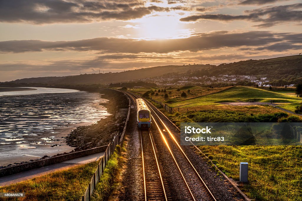 Train travelling past sea wall at sunset Train - Vehicle Stock Photo