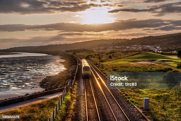 Train Travelling Past Sea Wall At Sunset Stock Photo - Download Image Now - Train - Vehicle, Public Transportation, Transportation