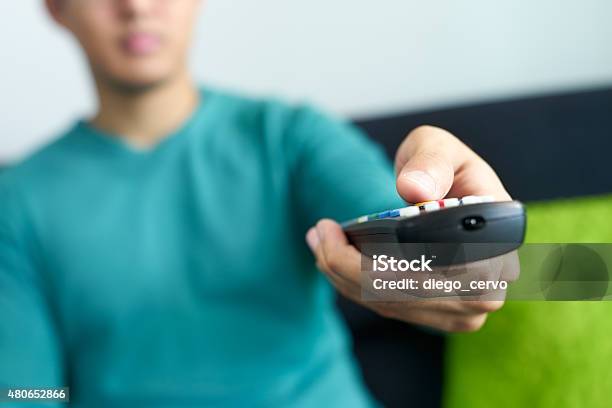 Asian Man Watches Tv Changes Channel Holding Remote Control Stock Photo - Download Image Now