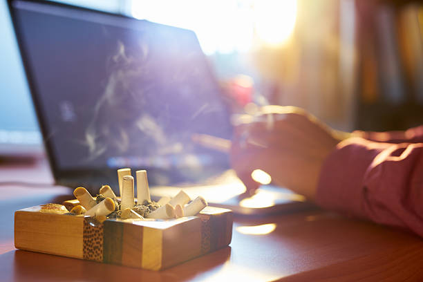 homem com laptop e fumar cigarro no escritório - nicotine healthcare and medicine smoking issues lifestyles imagens e fotografias de stock