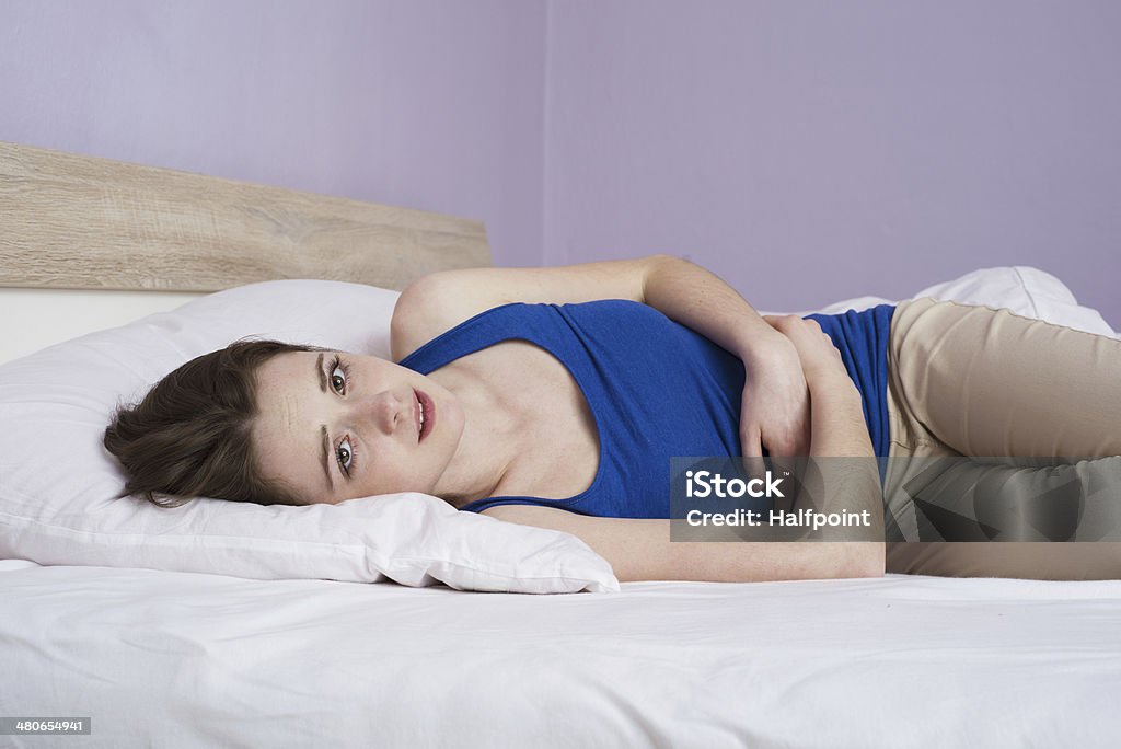 Sick woman Beautiful sad woman is lying on the bed. Adult Stock Photo