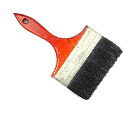 A vintage six inch wide paint brush with a wood handle on a white background.
